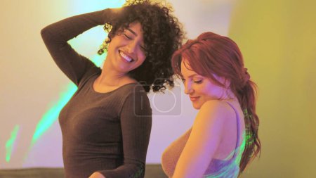 Photo for Two multi-ethnic sensual women dancing together in a home party - Royalty Free Image