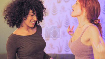 Photo for Latin and caucasian women dancing sensual in a night party at home - Royalty Free Image