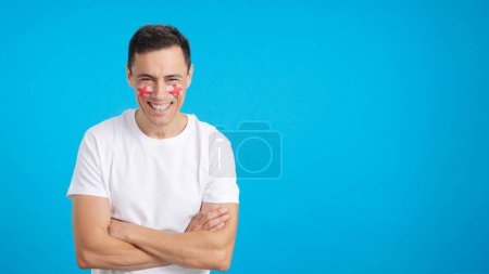 Man standing with english flag painted on face smiling with arms crossed