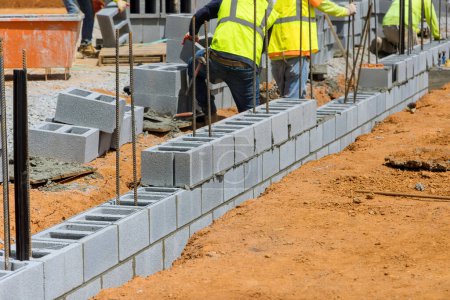 Foto de Una empresa albañil empleado albañil que establece el montaje de bloques de hormigón de pared que es parte del proyecto de construcción - Imagen libre de derechos