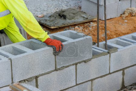 Photo for Bricklayer is putting down another row of cement blocks as part of construction process - Royalty Free Image