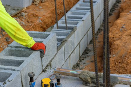 Photo for Another row of cement blocks is being laid down by bricklayer construction worker - Royalty Free Image