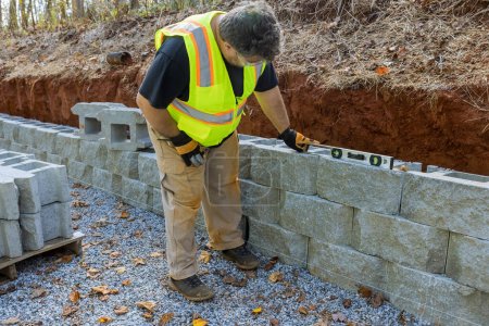 Edificio de herramientas de nivelación de hombre que conserva la pared de bloque de hormigón con ser construido en una propiedad nueva