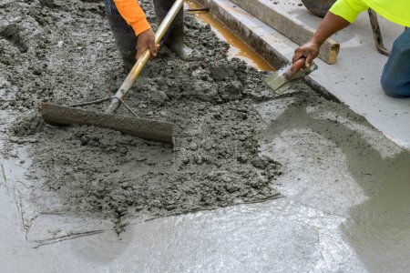 Foto de Trabajador de la construcción vertiendo cemento para crear una nueva acera en el lado de la casa - Imagen libre de derechos