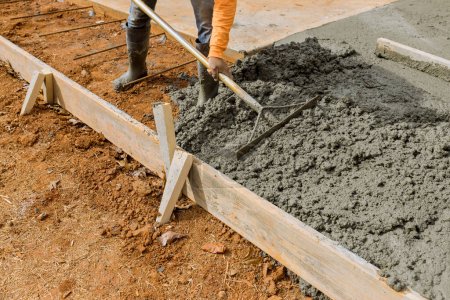 Photo for Workers pour cement around house on side of building to create an additional sidewalk for house - Royalty Free Image