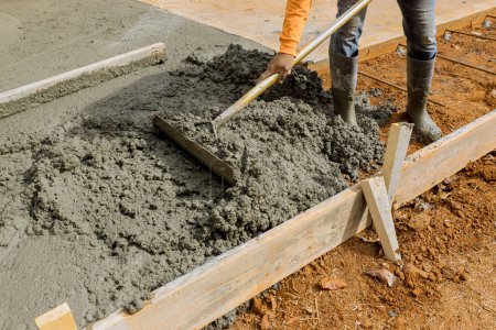 Trabajadores vierten cemento para crear una acera adicional para ser construido en el lado de la casa por el equipo de construcción