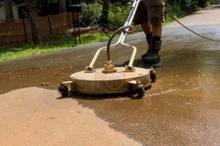 Using cleaning machine worker cleans street with help of high pressure washing machine