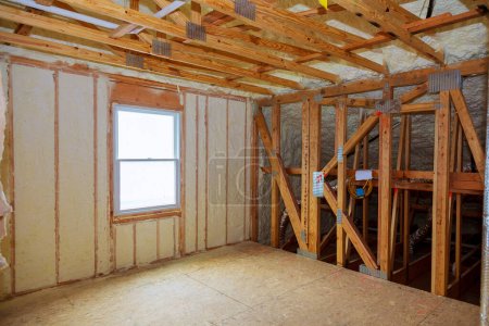 Téléchargez les photos : Isolation en mousse plastique installée dans le plafond incliné d'une nouvelle maison à ossature
. - en image libre de droit