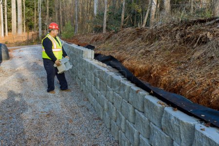Construction worker building retaining block wall being built on new property