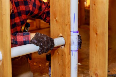 It is plumbing technician gluing PVC pipe to plastic pipe using cement glue for construction residential new home