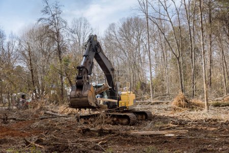 Téléchargez les photos : Il a fallu défricher les terrains des arbres déracinés autour des lotissements résidentiels dans les chantiers de construction à l'aide de patins tracteurs. - en image libre de droit