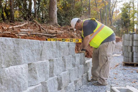 Téléchargez les photos : Bâtiment ouvrier de construction mur de soutènement en cours de construction sur une nouvelle propriété - en image libre de droit