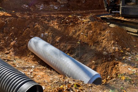 Foto de Worker laying sewage pipes in ground, preparing to put concrete pipes underground - Imagen libre de derechos