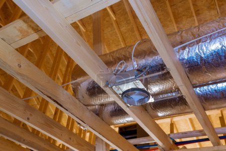 Photo for Ceiling inside new stick built home process of being built has ventilation pipes covered in silver insulation material - Royalty Free Image