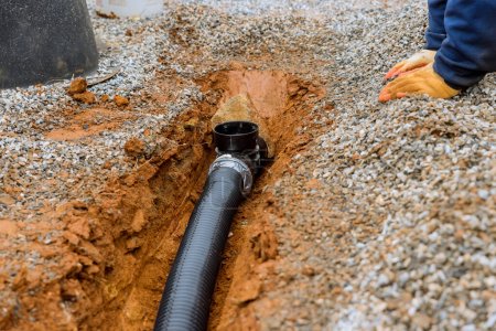 Téléchargez les photos : Mettre tuyau de drainage pour l'eau de pluie sur le trottoir de gravier du parking où le stationnement - en image libre de droit