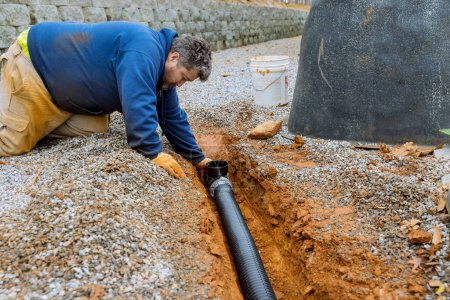 Foto de Assembling drainage pipe for rain water that is going to be used for rain water collection on covered parking space with gravel driveway - Imagen libre de derechos