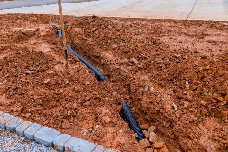 Foto de Drainage pipe for rain water is laid in lot of parking lot, which covered with gravel, driveway is sealed - Imagen libre de derechos