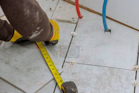 Photo for During preparation of laying floor tiles contractor measures ceramic tiles before they are cut into individual pieces - Royalty Free Image