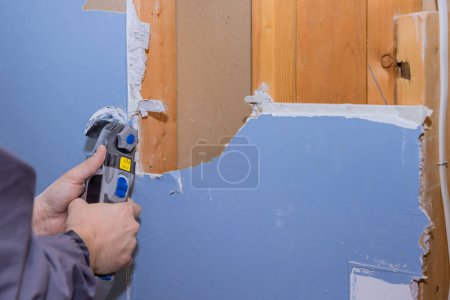 Téléchargez les photos : Au cours de la rénovation de la maison, la maison en placoplâtre a été coupée à l'aide d'un outil oscillant pour couper les plaques de plâtre endommagées. - en image libre de droit