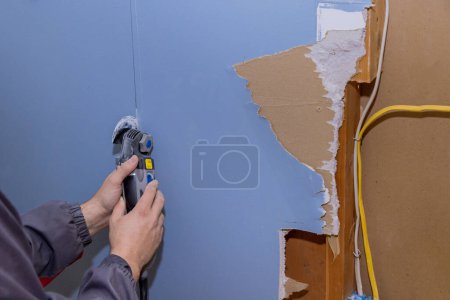 Téléchargez les photos : Travaux de rénovation dans la maison en coupant les plaques de plâtre endommagées à l'aide d'un outil multi oscillant - en image libre de droit