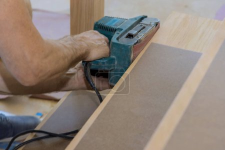 Téléchargez les photos : During construction carpenter works with new house grinding wooden staircase - en image libre de droit