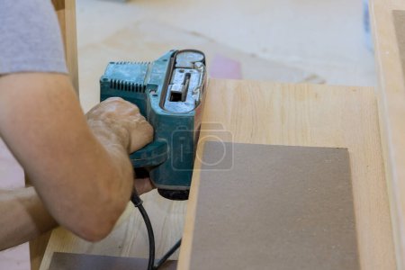 Téléchargez les photos : Carpenter works with in new house grinding wooden staircase - en image libre de droit