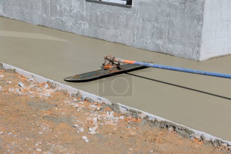 Téléchargez les photos : Worker plasters wet concrete floor using trowel after pouring concrete on surface - en image libre de droit