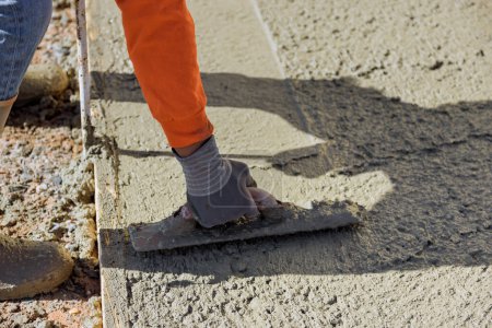 Foto de Después de verter trabajador de hormigón utiliza paleta para yeso piso de cemento de hormigón húmedo - Imagen libre de derechos