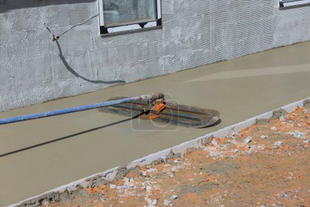 Téléchargez les photos : After pouring concrete over wet concrete surface worker plasters floor with trowel using - en image libre de droit