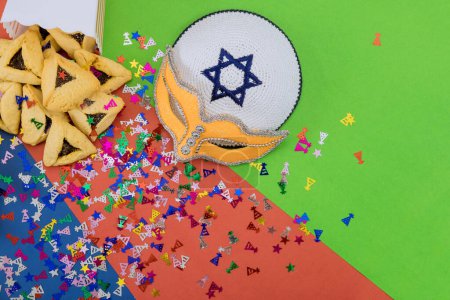 Téléchargez les photos : During Purim festival, Jews celebrate this religious holiday with cookies, tallit, noisemaker masks, and hamantaschen celebration symbols that remind them of holiday - en image libre de droit