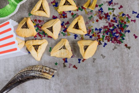 Téléchargez les photos : Symbols of celebration include hamantaschen cookies, shofar noisemakers tallits carnival masks during Jewish holiday Purim - en image libre de droit