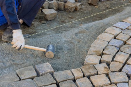 Téléchargez les photos : Paving of street with granite stones was laborious task that required skilled workers to use industrial cobblestones. - en image libre de droit