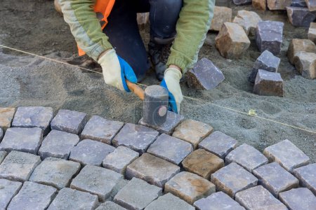 Foto de Worker were using industrial cobblestones to pave sidewalk with granite stones. - Imagen libre de derechos