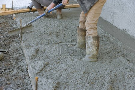 Photo for After pouring concrete employee used long trowels to level sidewalk. - Royalty Free Image