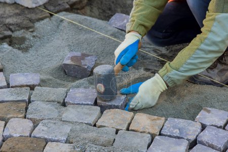 Téléchargez les photos : Pierre de granit utilisé pour la chaussée ont été soigneusement sélectionnés par les travailleurs pour leur durabilité de qualité pavés industriels - en image libre de droit