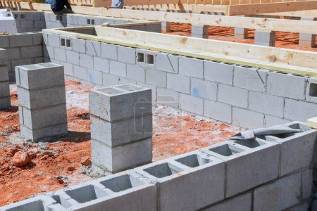 Hausbau beginnt auf Baustelle mit Fundamentmontage von Zementblöcken
