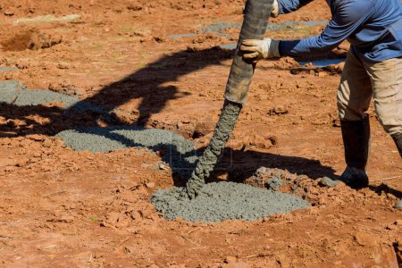 Photo for Concrete is poured for laying foundation of building by worker using an automatic pump to direct cement concrete - Royalty Free Image