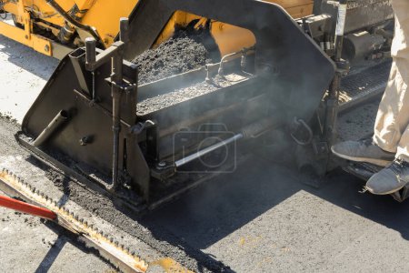 Téléchargez les photos : Pendant les travaux de construction de l'autoroute, un rouleau de route à vapeur de machine de revêtement d'asphalte est utilisé afin de recouvrir une nouvelle route. - en image libre de droit