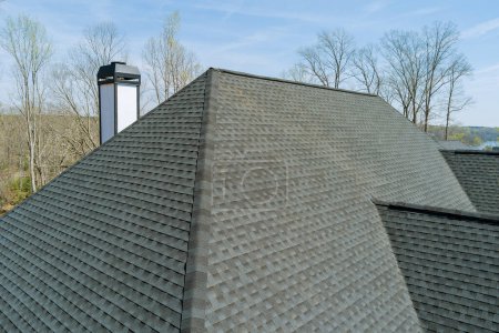 Im neuen Haus wird nach dem Einbau von Asphaltschindeln die Qualität der Dacharbeiten überprüft, um sicher zu gehen