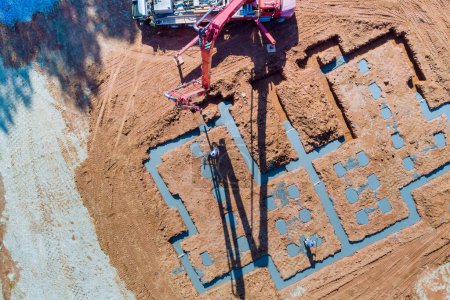 Photo for In course of construction house, concrete strip foundations are poured by using concrete pump to direct cement concrete into strips. - Royalty Free Image