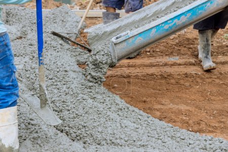 Photo for An employee is pouring wet concrete at new construction site on near new home to pave a driveway - Royalty Free Image