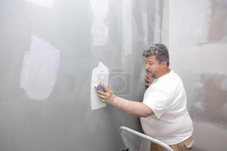 Foto de Durante la reparación, la mejora del hogar de un contratista de la habitación del apartamento lijó la pared después de poner - Imagen libre de derechos