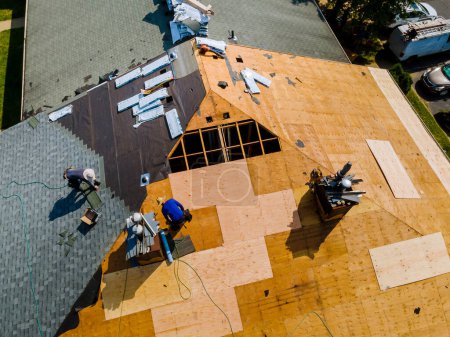Téléchargez les photos : Le toit de l'immeuble d'habitation a subi des réparations qui comprenaient l'installation de nouveaux bardeaux remplaçant l'ancien toit - en image libre de droit