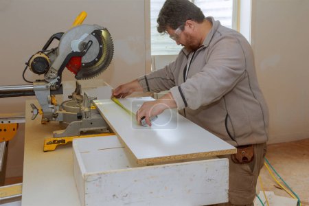 Foto de Un empleado usa sierra circular para cortar tableros de melamina para estantes con ayuda de sierra - Imagen libre de derechos