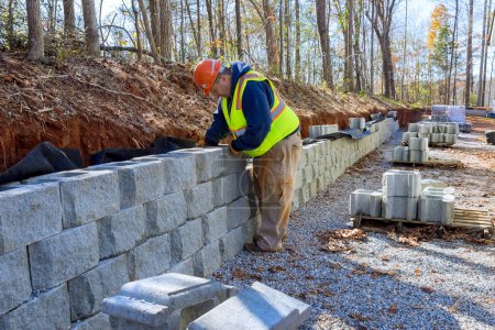 Téléchargez les photos : Les blocs de ciment sont utilisés par les travailleurs de la construction pour construire un mur de soutènement pendant le développement de nouvelles propriétés. - en image libre de droit
