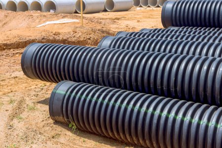 Stacked on construction site industrial large black plastic pipes sewerage prepared for installation