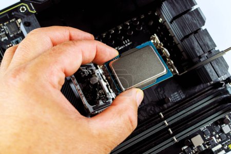 Photo for In process of assembling desktop computer, technician is plugging CPU into socket on motherboard. - Royalty Free Image