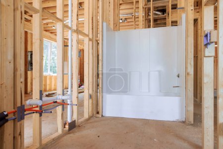 Neu hinzugefügte Acryl-Badewanne im im Bau befindlichen Haus Badezimmer inmitten eines Balkenrahmens