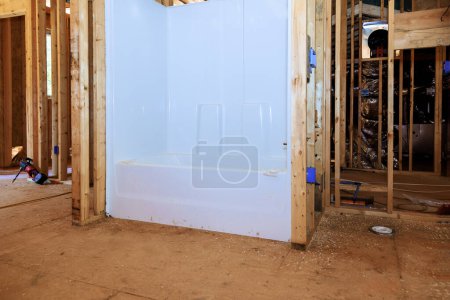 Téléchargez les photos : Maison émergente avec nouvelle salle de bain avec baignoire en acrylique installée entre un cadre de poutres - en image libre de droit