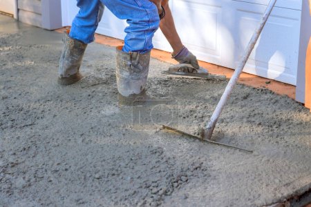 Photo for Concrete leveling workers on construction site with mix trowel leveling to concrete driveway - Royalty Free Image